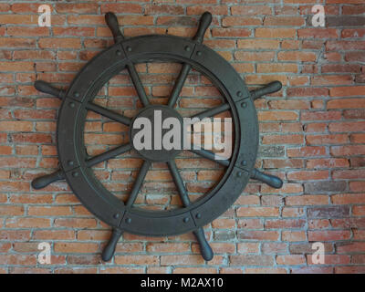 Rustique ancien vintage iron ship wheel sur fond brique Banque D'Images