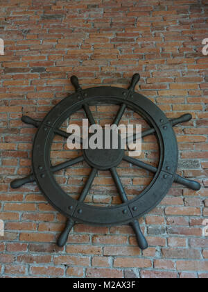 Rustique ancien vintage iron ship wheel sur fond brique Banque D'Images