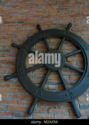 Rustique ancien vintage iron ship wheel sur fond brique Banque D'Images