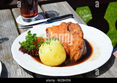 Schweinshaxe servi avec pommes de terre sautées (Bratkartoffeln) et la choucroute dans un restaurant bavarois dans les montagnes au-dessus de Tegernsee. Banque D'Images