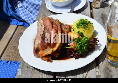 Schweinshaxe servi avec pommes de terre sautées (Bratkartoffeln) et la choucroute dans un restaurant bavarois dans les montagnes au-dessus de Tegernsee. Banque D'Images