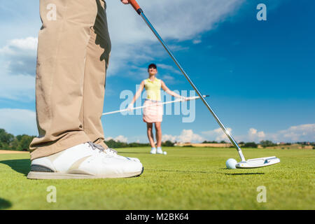 Close-up Vue de côté les pieds d'un joueur de golf professionnel masculin, prêt à frapper la balle avec un club de putter sur le green lors d'une difficile Banque D'Images