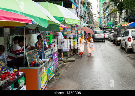 Garçon de deux moines novices, paire d'enfants moines, portant des robes rose, pied à Yangon street la collecte de dons et d'aumônes quotidiennes. La Birmanie, Myanmar Asie Banque D'Images