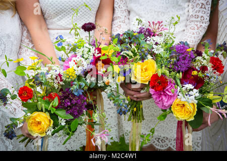 Bridesmaids holding bouquets de fleurs colorées, mid section, close-up Banque D'Images