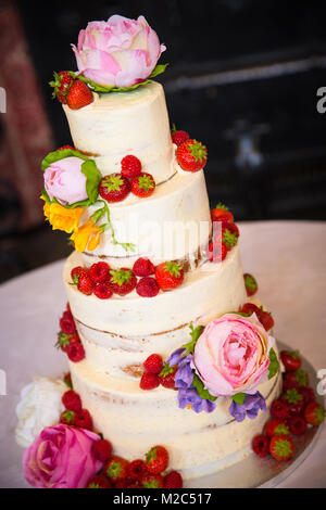 Des fleurs fraîches et des fruits sur gâteau de célébration à plusieurs niveaux Banque D'Images