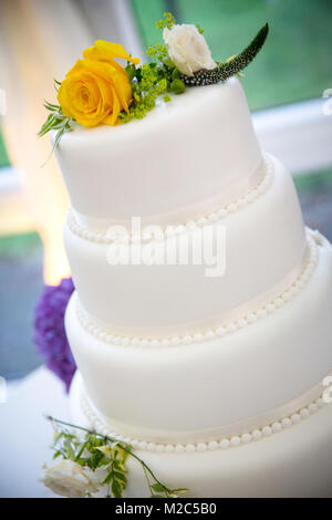 Les fleurs fraîches sur le dessus du gâteau de célébration à trois niveaux Banque D'Images