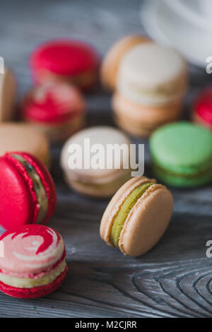 Macarons sur table en bois rustique, des bonbons français à base de meringue faite de blanc d'œuf, le sucre à glacer, le sucre, la poudre d'amande ou de masse d'amande et le colorant alimentaire Banque D'Images