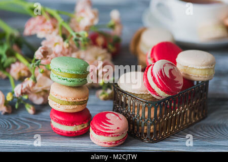 Macarons sur table en bois rustique, des bonbons français à base de meringue faite de blanc d'œuf, le sucre à glacer, le sucre, la poudre d'amande ou de masse d'amande et le colorant alimentaire Banque D'Images