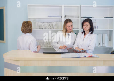 Les médecins ayant l'hôpital discussion pendant que les gens d'accueil assis en arrière-plan Banque D'Images