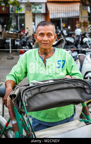 Friendly cycle cambodgienne locale conducteur de pousse-pousse à partir de la Cyclo Tour de ville dans une chemise verte à Phnom Penh, capitale du Cambodge, au sud-est de l'Asie Banque D'Images