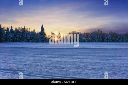 Coucher de soleil sur la pistes de ski de fond. Ciel dramatique par la lumière du soleil rougeoyant sur la forêt en arrière-plan. La Slovaquie, de l'Europe. Banque D'Images