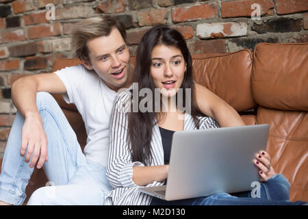 Surpris couple looking at laptop stupéfié par en ligne incroyable Banque D'Images