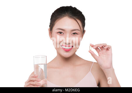 Smiling asian woman eating comprimés et de l'eau potable Banque D'Images