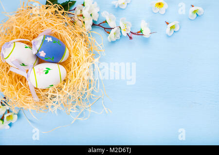 Oeufs de Pâques dans son nid sur fond de bois de couleur. La vie toujours avec des fleurs de Pâques, nid et les oeufs. Banque D'Images