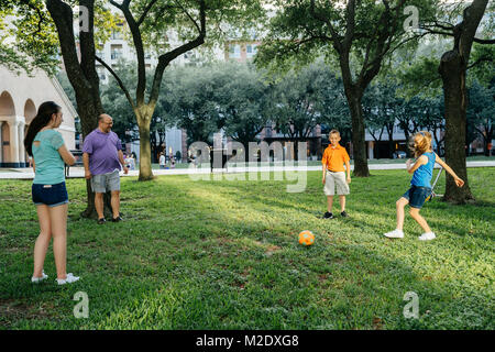 Caucasian family kicking soccer ball in park Banque D'Images