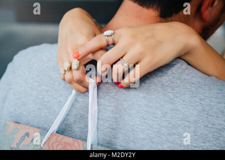 Mains d'Caucasian woman wearing rings hugging man Banque D'Images