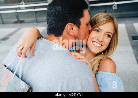 Caucasian man kissing joue de woman carrying Shopping bag Banque D'Images