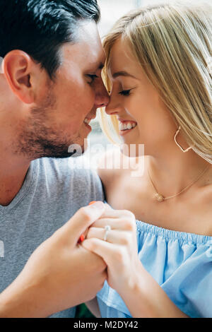 Smiling Caucasian couple holding hands and rubbing noses Banque D'Images