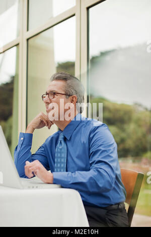Pensive Hispanic businessman using laptop in restaurant Banque D'Images