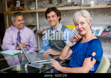 Portrait of smiling businesspeople using laptop in office Banque D'Images