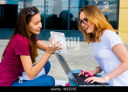 Les femmes de race blanche à l'aide d'ordinateur portable et tablette numérique en plein air Banque D'Images