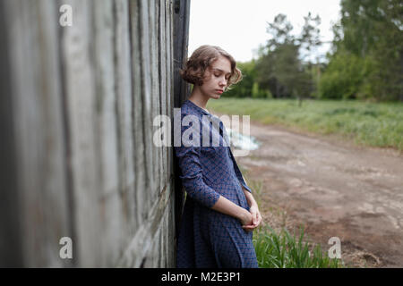 Pensive Caucasian woman leaning on wooden fence Banque D'Images