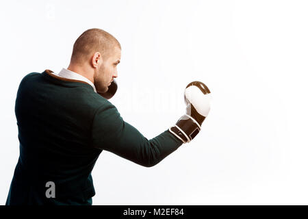 Jeune homme chauve, confident business man en chemise blanche, costume vert et des gants de boxe faisant un uppercut, boxe sur blanc fond isolé, sied voir Banque D'Images