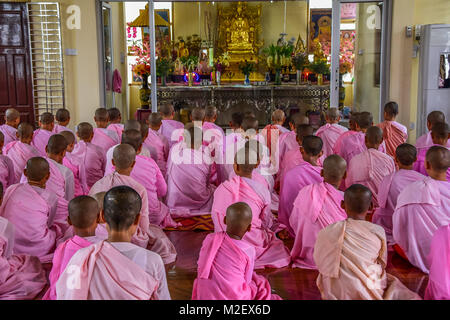 DAWEI, MYANMAR - 11 juillet 2015 : des religieuses en robe rose scandant en face de l'image de Bouddha dans un temple bouddhiste à Dawei du Myanmar. Banque D'Images