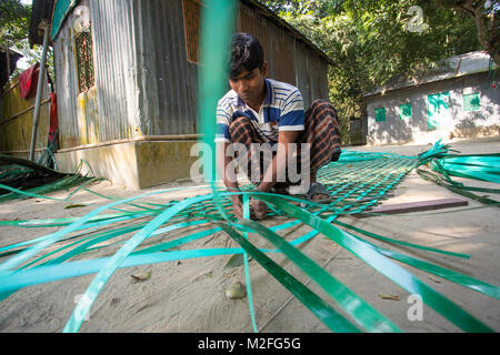 Le Bangladesh, Manikgonj. 7 Février, 2018. L'homme est un village dans la ville de weave. La profession de l'homme était en bambou ou le tissage du tissu, mais dans la ville il n'a pas obtenu tout le bambou ou en tissu de fils, il a choisi de faire du tricotage le gaspillage de plastique. Aujourd'hui, lui et ses enfants, tous ensemble, avec les matières plastiques. Il y a tant de familles de la région qui vivent leur vie de cette façon. Credit : Jahangir Alam Onuchcha/Alamy Live News Banque D'Images