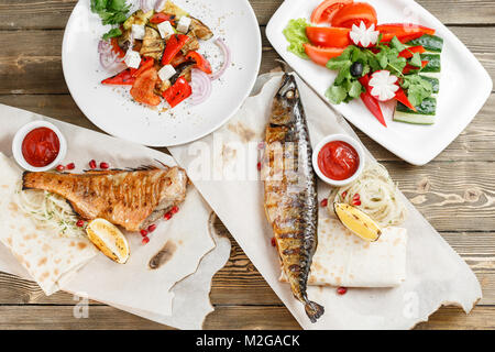 Le maquereau grillé et du bar. Salade de légumes frais. Servir sur une planche en bois sur une table rustique. Restaurant Barbecue menu, une série de photos de différentes viandes poissons anf Banque D'Images