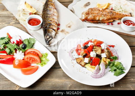 Le maquereau grillé et du bar. Salade de légumes frais. Servir sur une planche en bois sur une table rustique. Restaurant Barbecue menu, une série de photos de différentes viandes poissons anf Banque D'Images