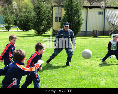 Région de la Marine commandant l'Europe, l'Afrique, l'Asie du Sud-Ouest maître commande Premier maître de Robert White joue un match de foot avec les étudiants de l'école Don C. Russolillo en plaine, en Italie, au cours d'un événement de Pâques à Carney, du parc de loisirs de 31 mars. White et d'autres membres de l'Association Premier maître de CNREURAFSWA a accueilli près de 60 étudiants dans le parc, faire le déjeuner et des événements comme des matches de football, un jeu de pinata et un rebond gonflable chambre. Le Premier Maître de CNREURAFSWA Association a organisé un événement de Pâques en plaine, l'Italie par l'EUCOM Banque D'Images