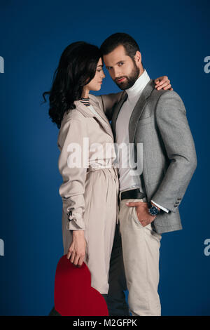 Couple holding morceau de papier en forme de cœur et s'étreindre isolé sur blue Banque D'Images