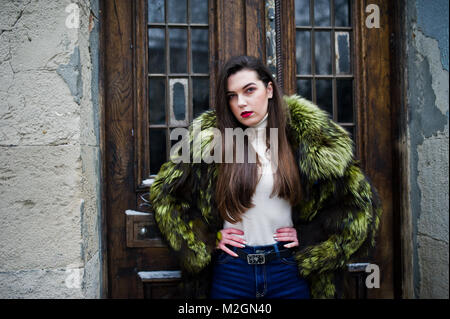 Brunette girl in green manteau de fourrure contre vieilles portes en bois. Banque D'Images