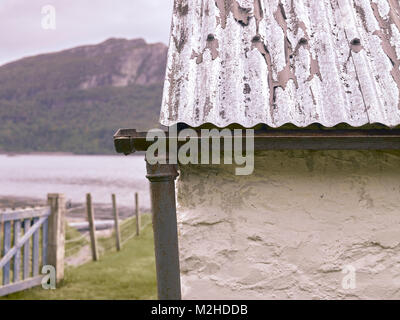 Détail de toit en tôle ondulée, fonte des gouttières et tuyaux vers le bas sur les rives du Loch Carron à Ardaneaskan Clachan Cottage. Banque D'Images