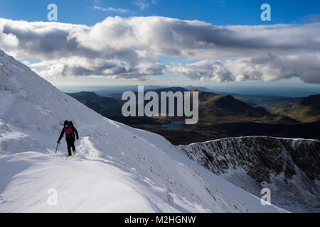 Female hiker randonnées sur chemin à Rhyd Ddu Bwlch sur Snowdon principal avec de la neige profonde en hiver dans le parc national de Snowdonia. Gwynedd, au nord du Pays de Galles, Royaume-Uni, Angleterre Banque D'Images