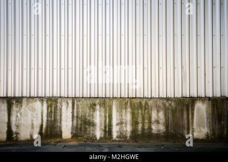 Metal Industriel mur gris rainuré sur base en béton Banque D'Images