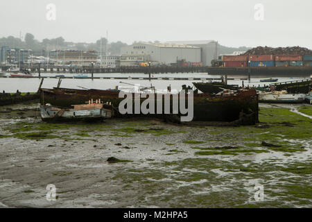 Itchen River, Southampton, à marée basse. Prises de la Northam Pont. Deux vieux bateaux délabrés au premier plan et un parc à ferrailles dans l'arrière-plan Banque D'Images