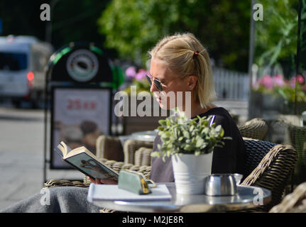 Une étudiante blonde lire un livre tout en buvant un café le matin. Oslo, Norvège Banque D'Images