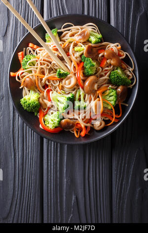 Nouilles soba d'frits avec des champignons, brocoli, carottes, poivrons libre sur une plaque sur une table. Haut Vertical Vue de dessus Banque D'Images