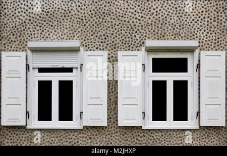 Deux nouvelles fenêtres blanches avec stores ouverts. Accueil mur décoré avec de petites pierres de granite. Verre isolé sur fond noir Banque D'Images