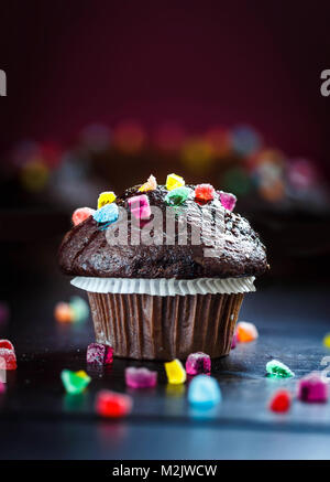 Muffin au chocolat délicieux et amusant avec des bonbons sur table en bois avec l'arrière-plan flou. Focus sélectif. Copier l'espace. Banque D'Images