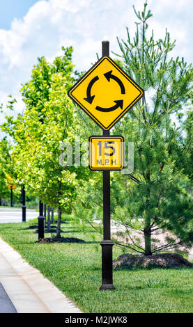 Shot vertical d'un rond-point, signe de la circulation avec vitesse limite signer ci-dessous dans un quartier du parc industriel. Les arbres verts avec trottoir en passant devant. Nuageux s Banque D'Images