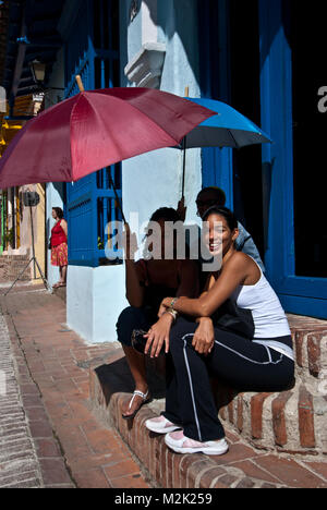 Jeune femme assise sur le long boradwalk d'escalier à l'ombre d'un parasol, Camagüey, Cuba Banque D'Images