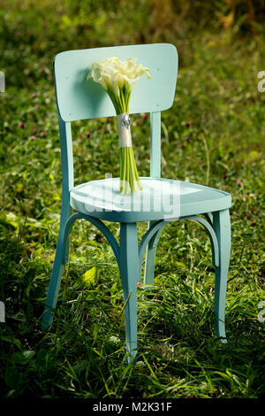 Bouquet de fleurs de lis calla blanc nature sur une chaise. Banque D'Images