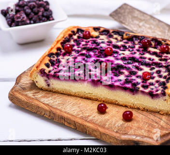 Un morceau de tarte au four de fromage cottage et de bleuets sur une planche de bois brun, vue latérale d'un tableau blanc Banque D'Images