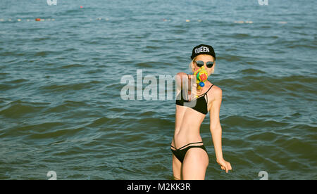 Happy young woman dans un bouchon avec le mot reine jouant avec canon à eau. Effet du film Banque D'Images