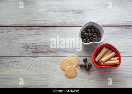 Deux bols en forme de coeur avec des petits gâteaux et bonbons sur vintage wooden surface. concept de célébration Jour de Valentines, morceau de l'amour, la saine alimentation biologique Banque D'Images