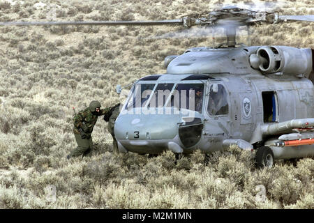 Côté gauche vue avant plan moyen comme lieutenant de la Marine US Brian J. Miller (partiellement montré dans un hélicoptère HH-60), ce pilote d'hélicoptère à l'Escadron anti-sous-marin 14, Atsugi, au Japon, est escorté dans un HH-60 Seahawk Hélicoptère Hélicoptère affecté à la lutte anti-sous-Squadron-Wing Pacifique, à la fin d'une autre opération de sauvetage réussie. Sauvetage du désert est la première recherche et sauvetage (SAR), la formation dispensée dans les champs de tir de Fallon Naval Air Station, Nevada. 000215-F-2829R-012 par navalsafetycenter Banque D'Images