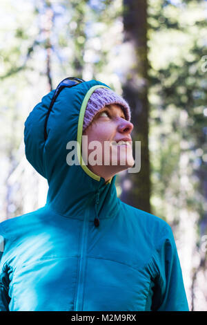 Young caucasian woman in winter clothing pose entre les arbres Séquoia géant Banque D'Images